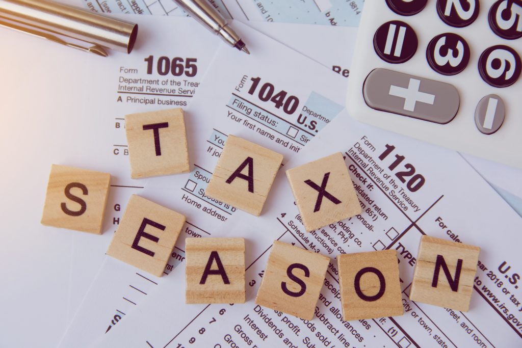 Tax season with wooden alphabet blocks, calculator, pen on 1040 tax form background